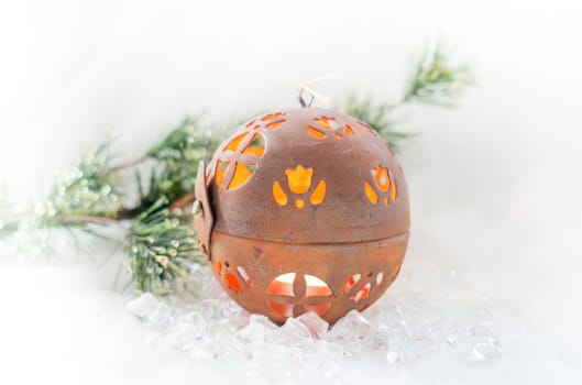 Spherical Christmas candle on ice with fir branch in the background