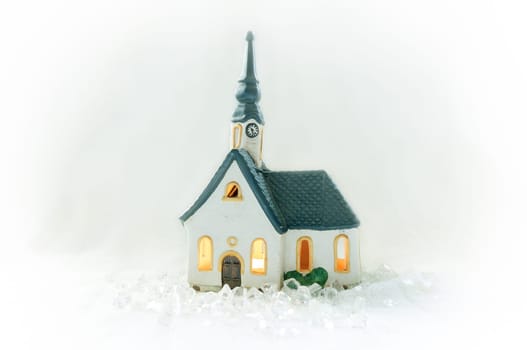 Illuminated miniature church in a snowy landscape surrounded by ice