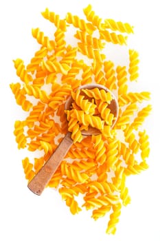 Italian raw spiral pasta and a wooden spoon, close-up shot from high angle, on white background