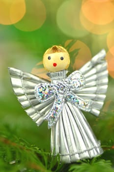 christmas decoration, silver angel made of straw against bokeh background