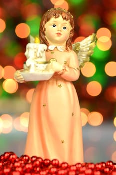 christmas decoration, figure of angel holding a candle against bokeh background