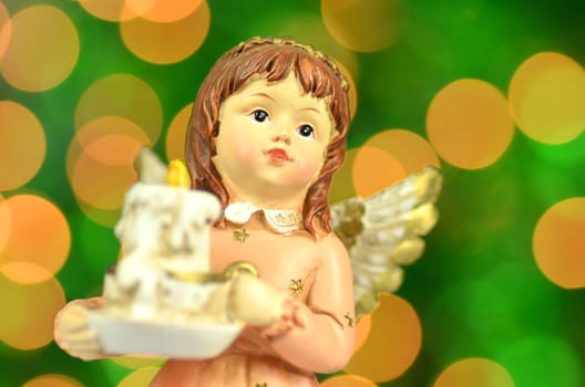 christmas decoration, figure of angel holding a candle against bokeh background