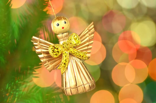 christmas decoration, golden angel made of straw against bokeh background