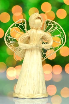 christmas decoration, golden angel made of straw against bokeh background
