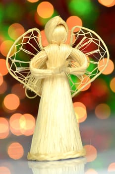 christmas decoration, golden angel made of straw against bokeh background