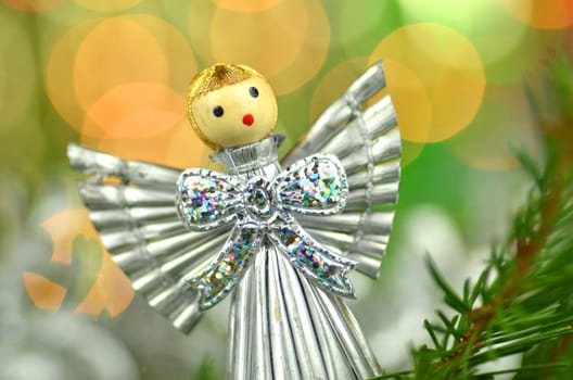 christmas decoration, silver angel made of straw against bokeh background