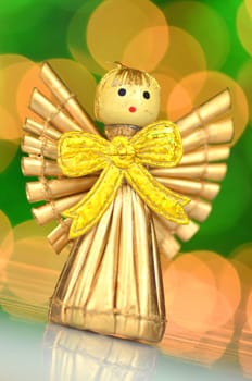 christmas decoration, golden angel made of straw against bokeh background