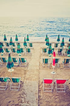 Shore beach with sun umbrella and deckchairs vintage look