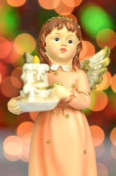 christmas decoration, figure of angel holding a candle against bokeh background