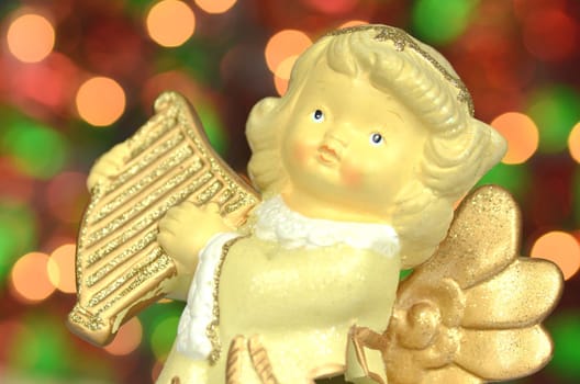 christmas decoration, figure of angel playing the harp against bokeh background