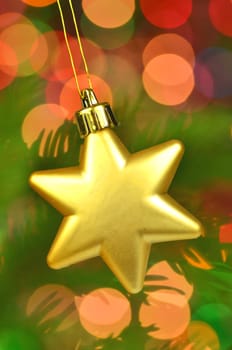 christmas decoration, golden Christmas star ball hanging on spruce twig against bokeh background