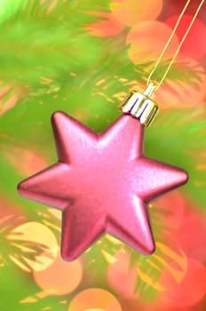 christmas decoration, pink Christmas star ball hanging on spruce twig against bokeh background