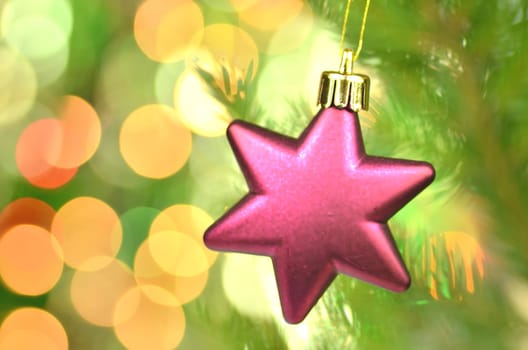 christmas decoration, pink Christmas star ball hanging on spruce twig against bokeh background