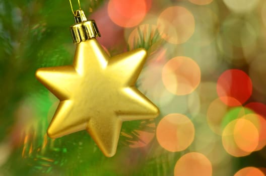 christmas decoration, golden Christmas star ball hanging on spruce twig against bokeh background