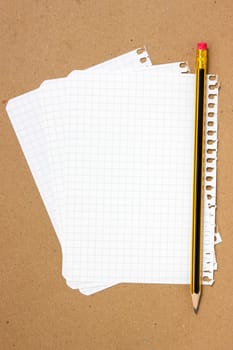 Notebook sheet and pencil on a brown paper background
