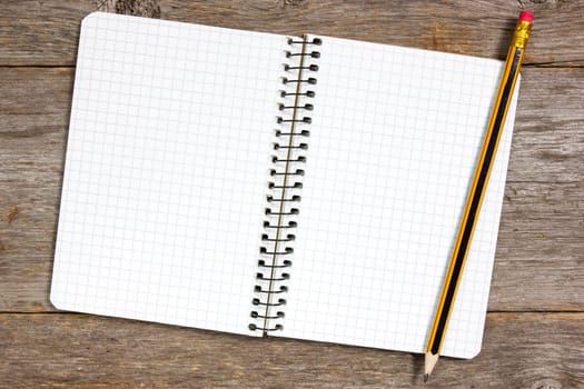 Spiral notebook and pencil on a wooden background