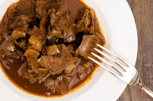 Fork with goulash and onions in a plate