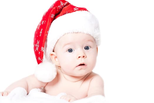 Baby girl lying on bed wearing red Santa hat