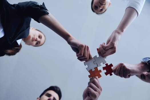 Group of business people assembling jigsaw puzzle and represent team support and help concept