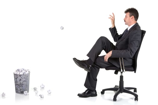 Businessman is throwing another paper ball into already full basket. Isolated on white.