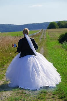 Bride in white wedding dress rides on a moped to the wedding ceremony