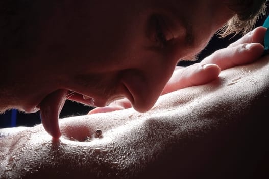 Young lovers in underwear tightly embraced and damp with sweat,he tenderly touches her belly button against a black background.
