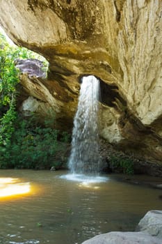 Tropical waterfall,water comes through a hole in the rock