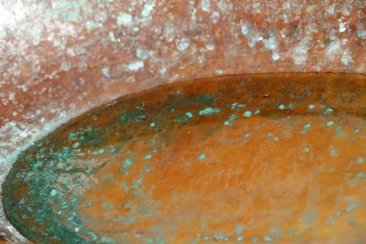 The close-up of holy water in a copper holy water basin.
