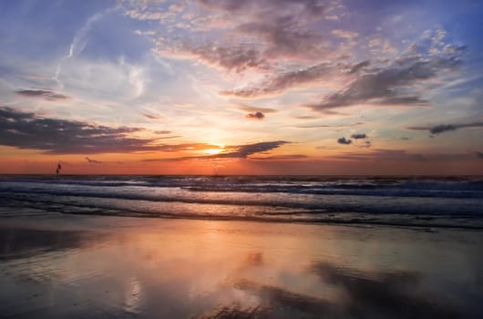 Colorful cloudy sunset at the beach with reflection - horizontal