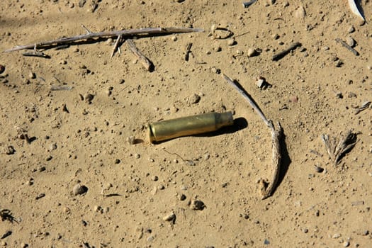 An used casing is lying in the dirt in the desert