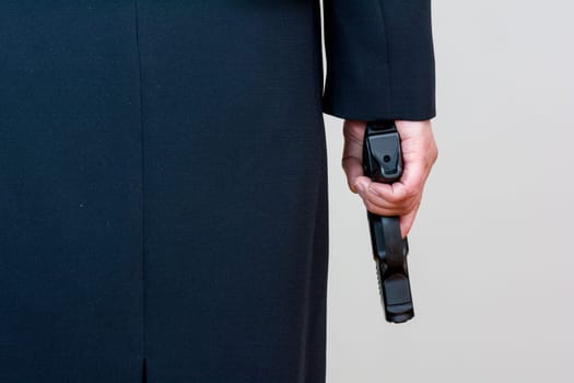 Close up of a the back side of a woman in business suit holding a hand gun