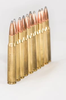 A few rifle bullets lined up in a row on white background