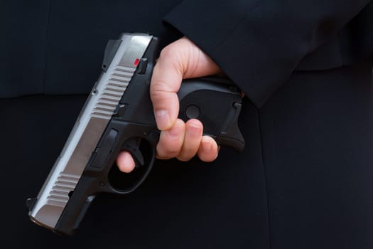 Close up with woman in business suit hold a pistol to dark suit