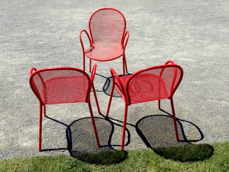 Three empty red metal chairs in a circle