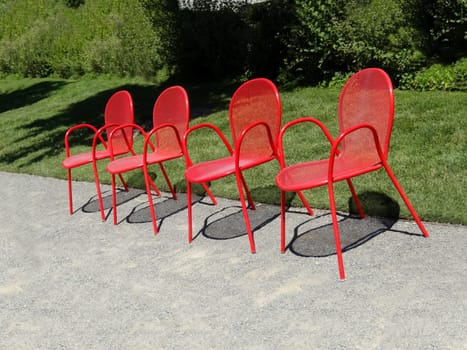 Four empty red metal chairs in a row