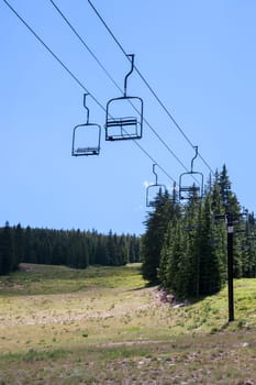 Empty ski lift seats in alpine summer landscape