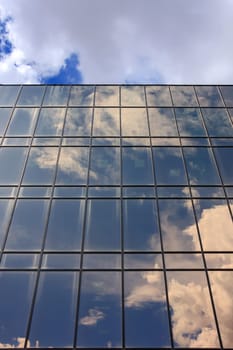 Reflections of clouds and sky on a shiny surface over sky
