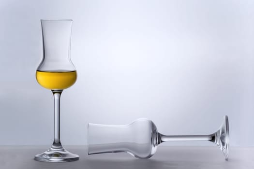 One empty Grappa glass lying and one filled standing