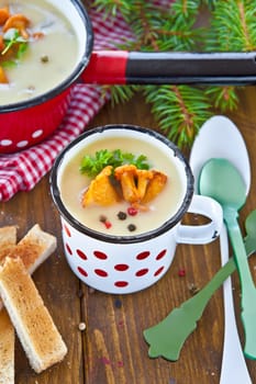 Creamy mushroom soup in cup with fresh chanterelles