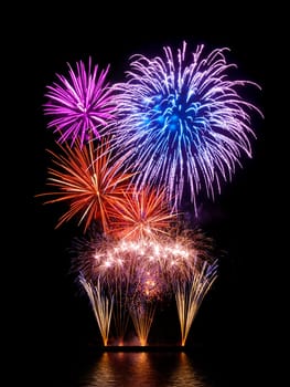 Magnificent colorful fireworks on black with reflection on water