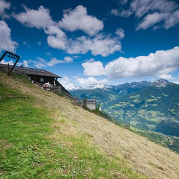 View of the Merano Valley towards the village of Scena from the village of Tyrol in summer with blue sky and white clouds