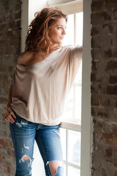 Attractive young woman standing by the window