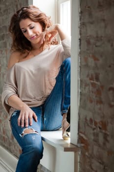 Attractive young woman sitting on the window sill