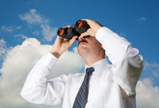Businessman is looking ahead through binoculars with sky in the background