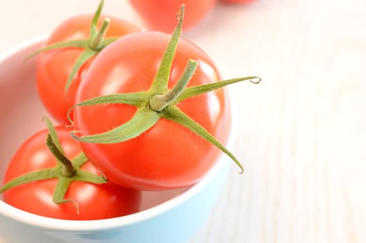 Fresh red tomatoes in a blue bowl on a wooden table