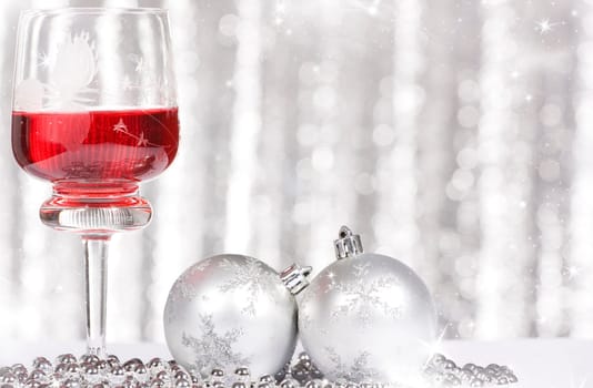 Red wine and Christmas balls against silver background