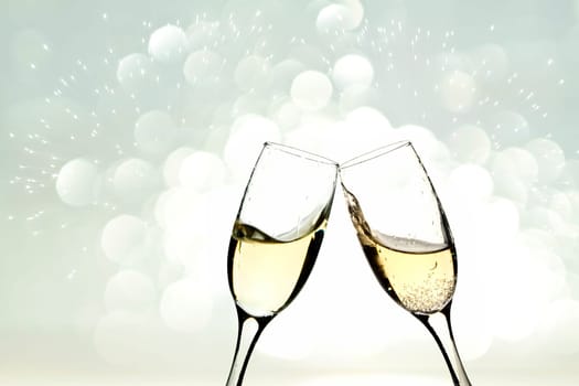 Glasses with champagne against holiday light and snowflakes