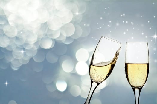 Glasses with champagne against holiday light and snowflakes