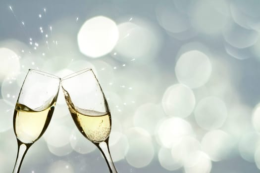Glasses with champagne against holiday light and snowflakes