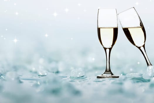 Glasses with champagne against holiday light and snowflakes